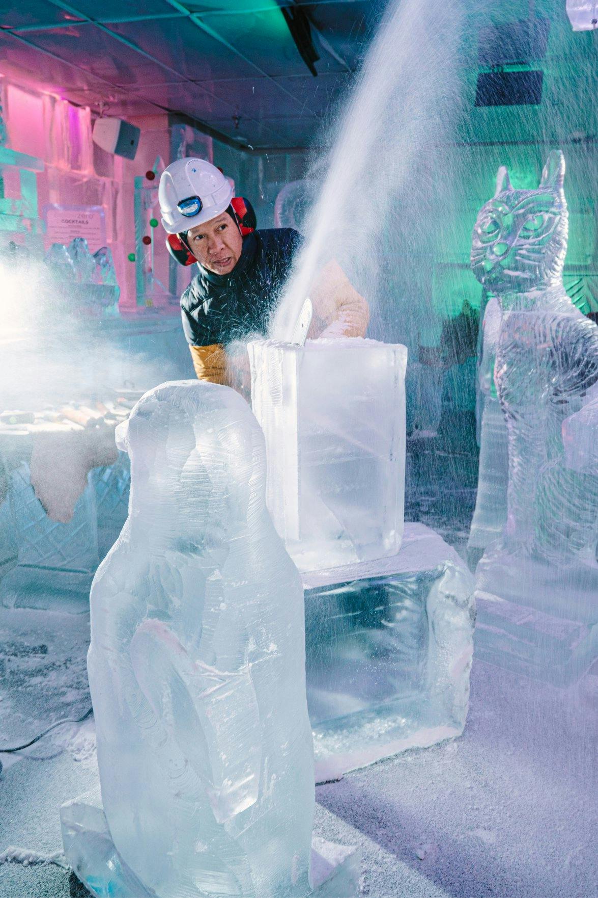 Ice sculptor carving an ice sculptor of a penguin